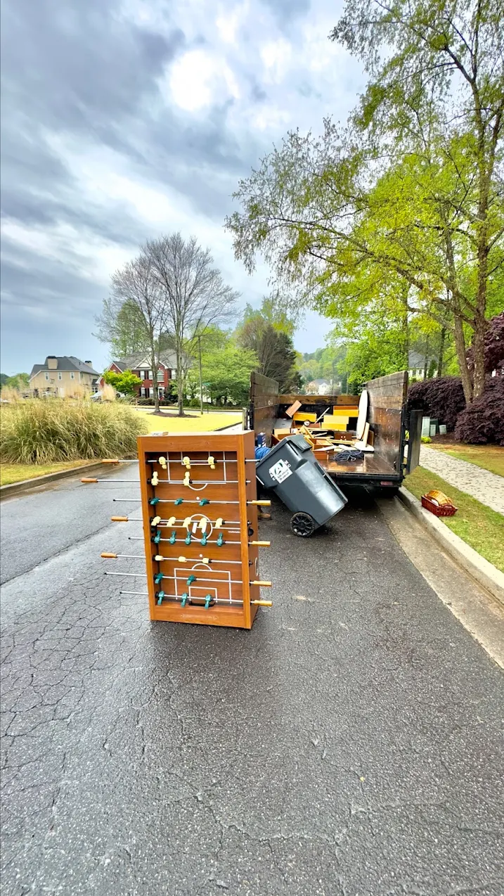 A foosball table and household junk being loaded into the Junk Dads truck