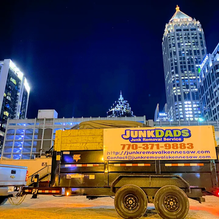 Junk Dads dump trailer on a night job in front of city high-rises
